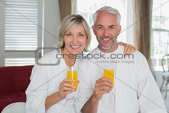 Happy mature couple holding orange juices