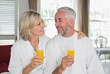 Happy mature couple holding orange juices