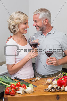 Loving mature couple with wine glasses in kitchen