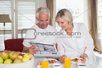 Couple reading newspaper at breakfast table