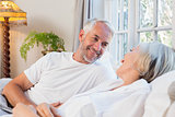 Happy mature couple relaxing in bed
