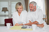 Cature couple sitting with home bills and calculator