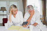 Worried mature couple with home bills and calculator