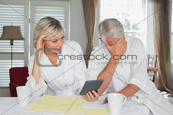 Worried mature couple with home bills and calculator