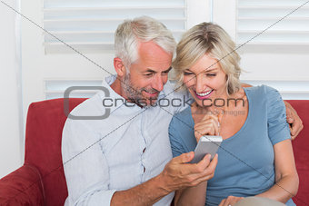 Smiling mature couple reading text message