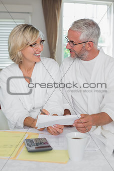 Happy couple sitting with home bills and calculator