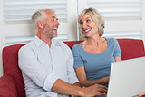 Cheerful mature woman using laptop in the living room