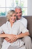 Mature man embracing woman from behind in living room