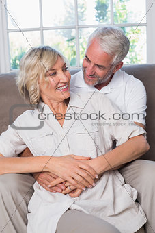 Mature man embracing woman from behind in living room