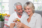 Happy mature couple with a flower in living room
