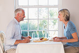 Side view of mature couple having food by window