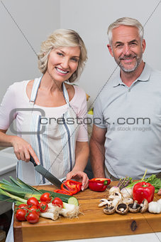 Happy mature couple preparing food in kitchen
