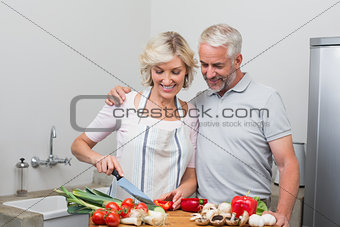 Happy mature couple preparing food together in kitchen