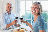 Portrait of a mature couple toasting wine glasses over food