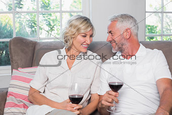 Happy relaxed mature couple with wine glasses in living room