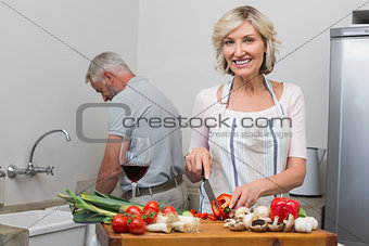 Happy mature couple preparing food together in kitchen