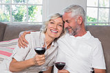 Loving mature couple with wine glasses in living room