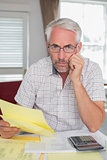Serious mature man with home bills and calculator