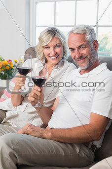 Happy mature couple with wine glasses in living room