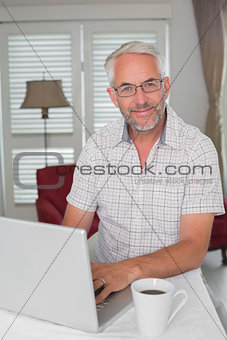 Smiling mature man using laptop at home