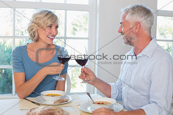 Happy mature couple toasting wine glasses over food