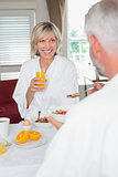 Smiling mature woman having breakfast with cropped man