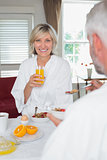 Smiling mature woman having breakfast with cropped man
