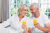 Mature couple holding orange juices at home