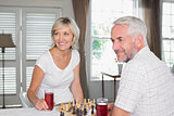 Mature couple looking away while playing chess