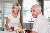 Mature couple looking away while playing chess