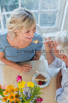 Mature man feeding happy woman pastry