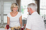 Happy mature couple playing chess at home