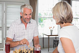 Mature couple with drinks while playing chess