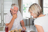 Serious mature couple playing chess at home