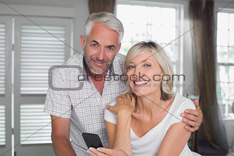 Happy mature couple reading text message at home