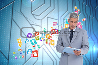 Composite image of serious businessman using tablet pc looking at camera
