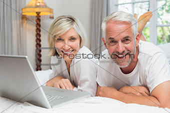Portrait of a mature couple using laptop in bed