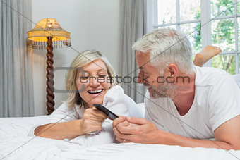 Cheerful mature couple reading text message