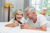 Cheerful mature couple reading text message at home