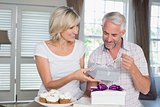 Happy woman giving a gift box to mature man
