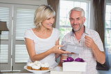 Happy woman giving a gift box to mature man