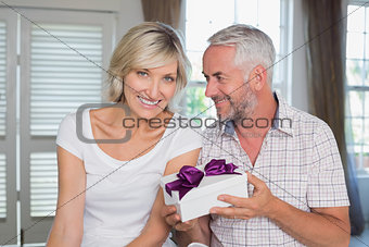 Happy mature couple with a gift box at home