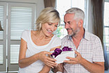 Happy mature couple with a gift box at home