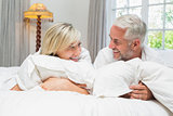 Happy mature couple lying in bed at home