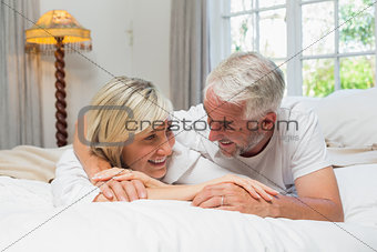 Happy mature couple lying in bed at home