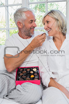 Loving mature man feeding woman chocolates