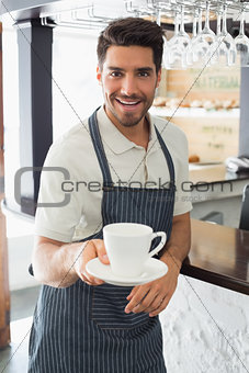 Smiling waiter holding coffee cup at café