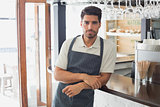 Serious confident young waiter at cafe counter