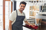 Smiling waiter cleaning countertop with sponge