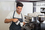 Waiter smiling and making cup of coffee at coffee shop